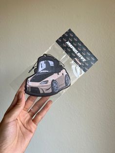 a hand holding up a sticker with a car on it's back end