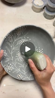 a person is using a mouse to decorate a bowl with flowers on the side and leaves on the inside