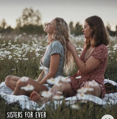 two women are sitting in the grass together