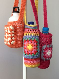 three crocheted purses hanging from a hook on a white pole in front of a wall