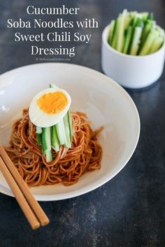 a white plate topped with noodles and an egg sitting on top of it next to chopsticks