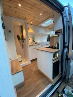 the interior of a camper van with its door open and kitchen area visible from inside