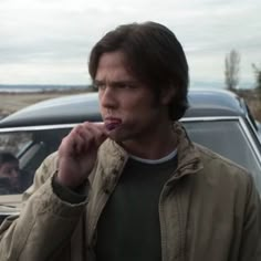 a man brushing his teeth in front of a car