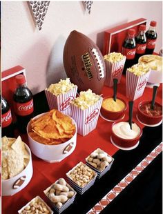 a football themed party with snacks, dips and crackers on a red table cloth