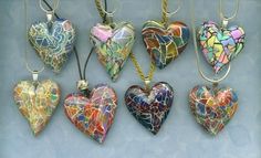 six heart shaped glass ornaments hanging from strings on a blue background with the words love written below them