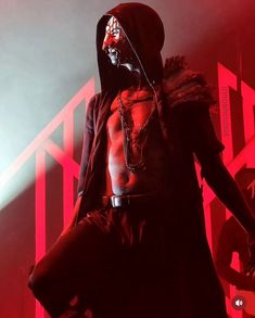 a man wearing a hoodie and holding a knife in his hand while standing on stage