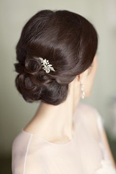 a woman wearing a hair comb with flowers on it's head and her hair in a low bun