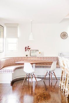 an image of a room with furniture on the floor and in the background, there is a large circular table surrounded by white chairs