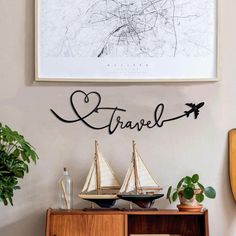 a wooden cabinet sitting next to a wall with a painting above it and two boats on top