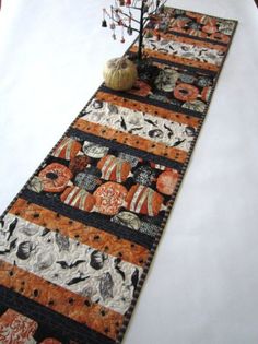 the table runner is decorated with pumpkins and other decorative items, including a small tree