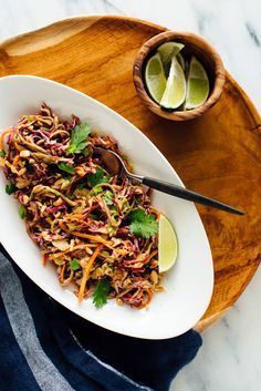 a white bowl filled with noodles and garnished with cilantro on a wooden tray