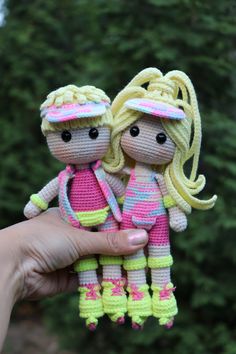 two crocheted dolls are being held by someone