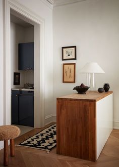 a room with a table, lamp and pictures on the wall next to an area rug