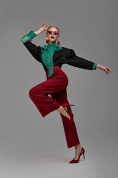 a woman in red pants and green shirt is dancing