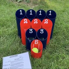 several buckets with numbers on them sitting in the grass next to a tennis ball