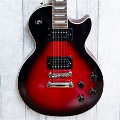 a red and black electric guitar hanging on a white wooden wall with the strings down