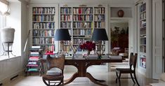 a dining room table with two lamps on it and bookshelves in the background