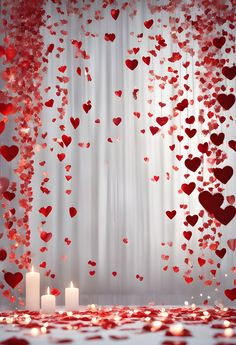 two candles are sitting on a table with hearts falling from the ceiling and curtains in the background