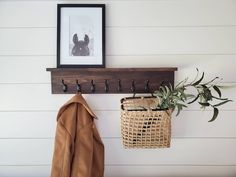 a coat rack with two coats hanging from it and a basket on the wall next to it