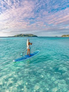 a woman riding on top of a paddle board in the ocean