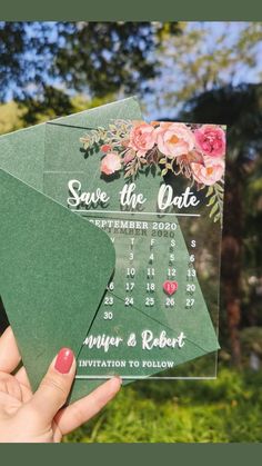 a person holding up two green envelopes with flowers on them, and the date card is