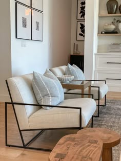 a living room with white couches and wooden coffee table in front of the wall