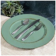 two forks and spoons are sitting on a plate with a plant in the background