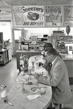 a man sitting at a table in front of a counter with food on top of it