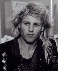 a black and white photo of a man with long blonde hair sitting on a carousel