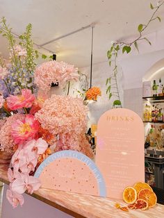 a counter with flowers, oranges and menu on it in front of a store