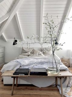 a bed room with a neatly made bed and a vase filled with flowers on top of it