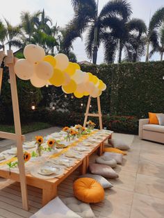 a table set up with sunflowers and balloons for an outdoor dinner or party