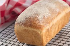 a loaf of bread sitting on top of a cooling rack next to a red and white checkered napkin