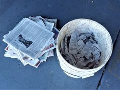 a bucket full of newspapers sitting on the ground