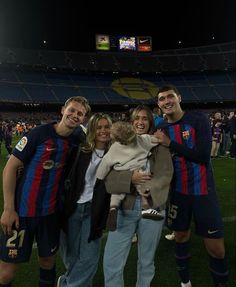 a group of people standing next to each other on top of a soccer field at night