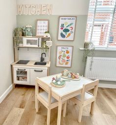 a small kitchen with wooden floors and white walls, including a dining table set for two