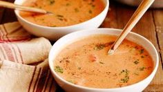 two bowls filled with soup on top of a wooden table