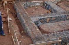 a man standing in front of a building with bricks and wire on the ground next to it