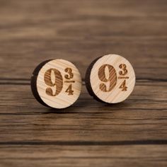 two wooden earrings with numbers on them sitting on top of a wood table next to each other