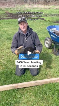 a man kneeling down in the grass next to a wheelbarrow with an inscription on it