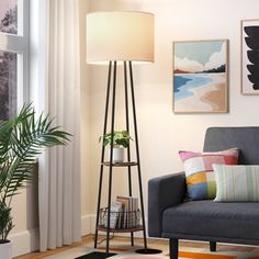 a living room with a couch, lamp and pictures on the wall above it in front of a window