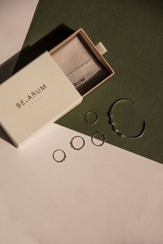 three pairs of silver rings in a gift box with the packaging open next to them