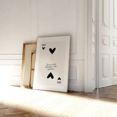 two framed pictures sitting on the floor in front of a white wall with an open door