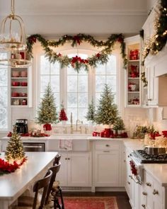 a kitchen decorated for christmas with red and green garland on the windowsills, candles and trees