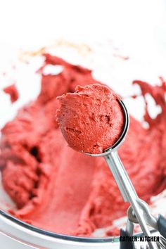 a spoon full of red cake batter in a bowl