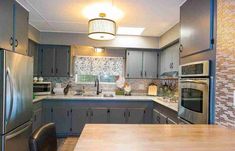 a kitchen with gray cabinets and stainless steel appliances