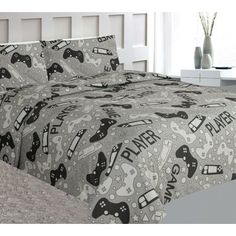 a bed covered in a gray and black comforter with video game themed sheets on it