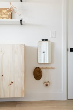 a white room with a wooden cabinet and mirror on the wall next to a hat rack