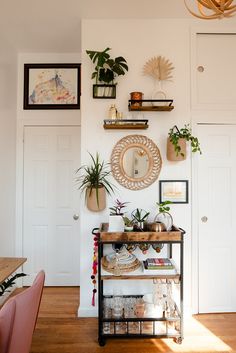 a room with some plants on the wall and pictures above it, along with other items