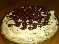 a cake with white frosting and chocolate toppings on a wooden table, ready to be eaten